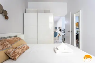a white bedroom with a white bed and a mirror at Casa Lua by Cadiz Time in Cádiz