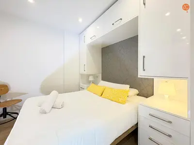 a white bedroom with a large bed with yellow pillows at La Suite de la Laguna Grupo AC Gestion in Cádiz