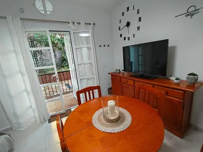 a dining room with a wooden table and a television at Villa Playa in Novo Sancti Petri