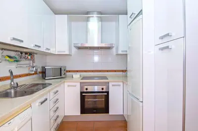 a white kitchen with a sink and a microwave at Casa Albatros, Apartamentos Living Sur in Sanlúcar de Barrameda
