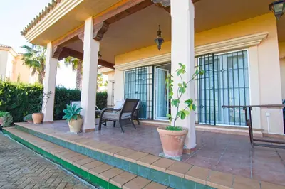 a porch of a house with a chair and a table at Casa Albatros, Apartamentos Living Sur in Sanlúcar de Barrameda