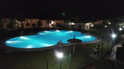 a large blue swimming pool at night at Casa Albatros, Apartamentos Living Sur in Sanlúcar de Barrameda