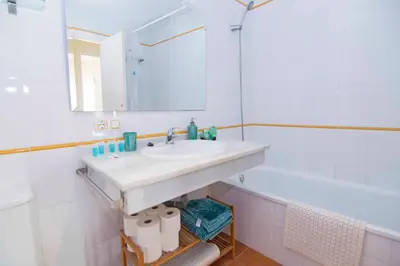 a bathroom with a sink and a tub and a mirror at Casa Albatros, Apartamentos Living Sur in Sanlúcar de Barrameda