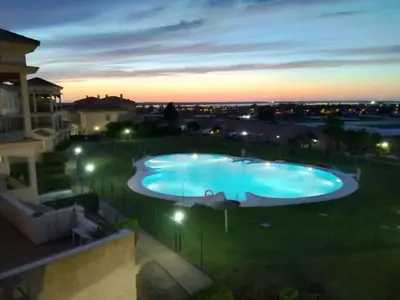 a large swimming pool in a yard at night at Casa Albatros, Apartamentos Living Sur in Sanlúcar de Barrameda