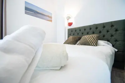 a white bed with a black headboard and pillows at Estudio Las Lavanderas de Cádiz in Cádiz