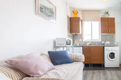 a living room with a couch and a kitchen at Estudio Las Lavanderas de Cádiz in Cádiz