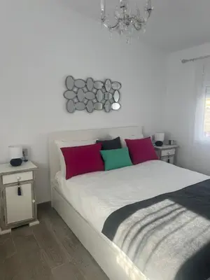 a white bed with colorful pillows in a bedroom at Dante Suite in Jerez de la Frontera