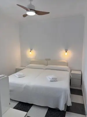 a bedroom with a white bed with a ceiling fan at Apartamento Clavel in Chipiona
