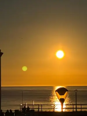 a sunset on the beach with the sun setting at Apartamento Clavel in Chipiona