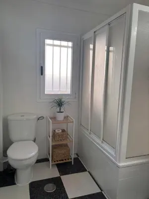 a white bathroom with a toilet and a window at Apartamento Clavel in Chipiona