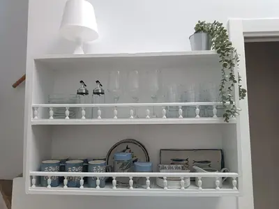 a white shelf with dishes and glasses and a lamp at San Miguel in San Fernando