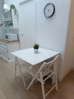 a white table and a chair with a clock on the wall at San Miguel in San Fernando