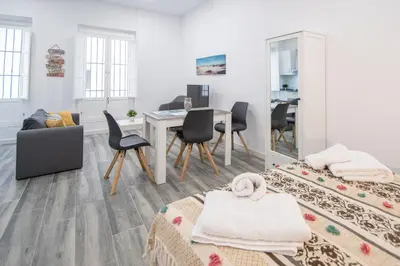 a white living room with a table and chairs at Estudio Viñamar Cádiz in Cádiz
