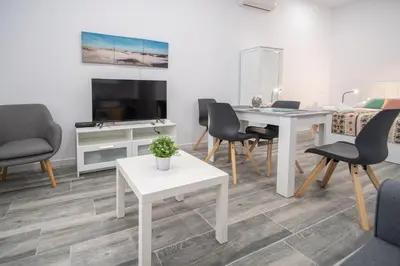 a living room with a white table and chairs at Estudio Viñamar Cádiz in Cádiz
