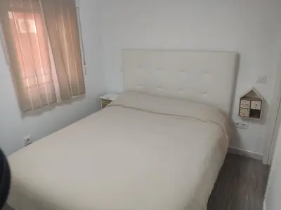 a white bed in a small room with a window at Apartamento Santa Teresa in Cádiz