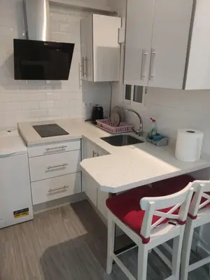 a kitchen with white cabinets and a sink and two chairs at Apartamento Santa Teresa in Cádiz