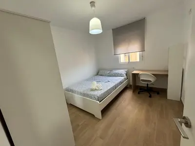 a small bedroom with a bed and a desk at Cachucha Apartment in Puerto Real