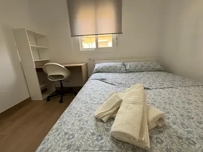 a bedroom with a bed and a desk and a chair at Cachucha Apartment in Puerto Real