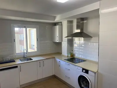 a white kitchen with a sink and a washer at Cachucha Apartment in Puerto Real