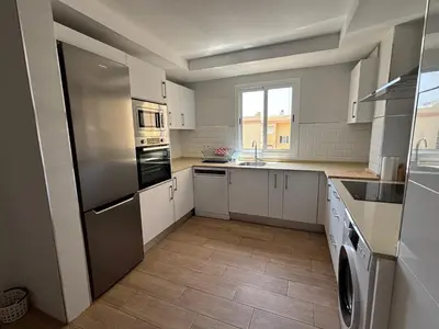 a kitchen with white cabinets and a stainless steel refrigerator at Cachucha Apartment in Puerto Real