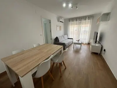 a living room with a wooden table and chairs at Cachucha Apartment in Puerto Real