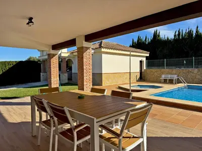 a patio with a wooden table and chairs next to a swimming pool at El Bosque del Duende - Ole Solutions in Arcos de la Frontera