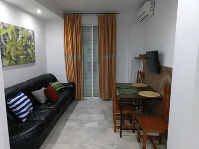 a living room with a black leather couch and a table at Apartamento Al Sur del Sur in Sanlúcar de Barrameda