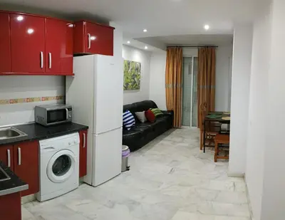 a kitchen and living room with red cabinets at Apartamento Al Sur del Sur in Sanlúcar de Barrameda