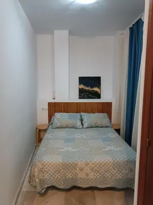 a bedroom with a bed with a blue comforter at Apartamento Al Sur del Sur in Sanlúcar de Barrameda