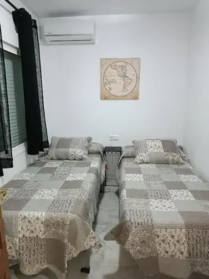 a bedroom with two beds and a picture on the wall at Apartamento Al Sur del Sur in Sanlúcar de Barrameda