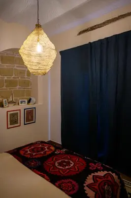 a bedroom with a bed with a blue curtain and a chandelier at Casa Del Encanto Arcos in Arcos de la Frontera