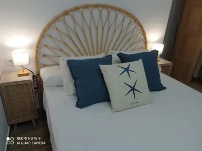 a bed with blue and white pillows on it at Apartamento Mar III in San Fernando