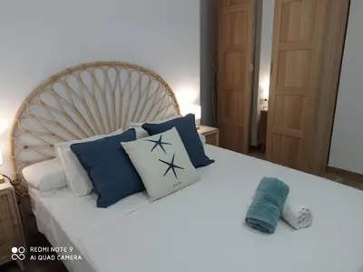 a bed with blue and white pillows on it at Apartamento Mar III in San Fernando