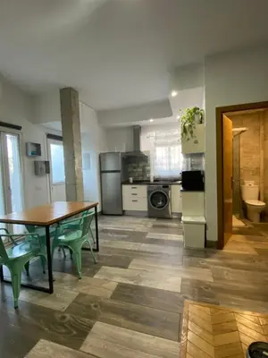 a kitchen with a table and green chairs in a room at Estudio playa la muralla in El Puerto de Santa María