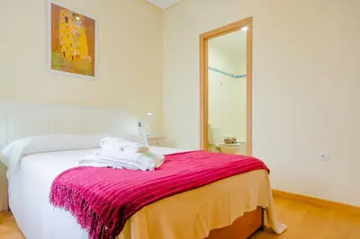 a bedroom with a bed with a pink blanket at Apartamentos Ribera del Puerto in El Puerto de Santa María