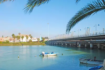 a boat in the water next to a bridge at Apartamentos Ribera del Puerto in El Puerto de Santa María
