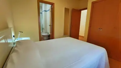 a bedroom with a white bed and a bathroom at Apartamentos Ribera del Puerto in El Puerto de Santa María