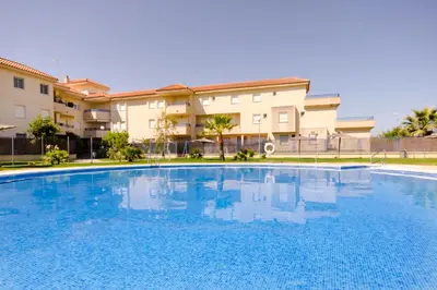 a large blue swimming pool in front of a building at Apartamentos Sanlúcar & Doñana in Sanlúcar de Barrameda