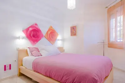 a bedroom with a bed with pink sheets and roses on the wall at Apartamentos Sanlúcar & Doñana in Sanlúcar de Barrameda