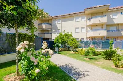 an apartment building with a garden in front of it at Apartamentos Sanlúcar & Doñana in Sanlúcar de Barrameda