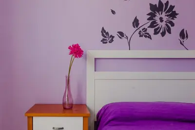a vase with a flower on a table next to a bed at Apartamentos Sanlúcar & Doñana in Sanlúcar de Barrameda