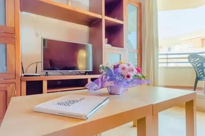 a table with a book and flowers on it at Apartamentos Sanlúcar & Doñana in Sanlúcar de Barrameda
