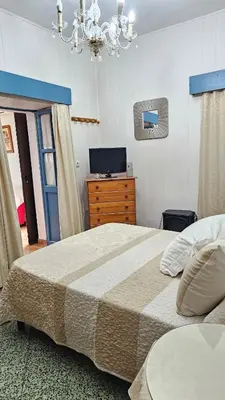 a bedroom with a bed and a dresser and a television at Casa de la Abuela Rosario in Sanlúcar de Barrameda
