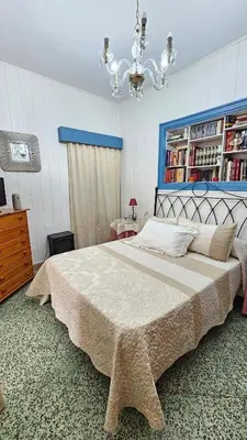 a bedroom with a large bed and a chandelier at Casa de la Abuela Rosario in Sanlúcar de Barrameda