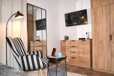 a bedroom with a chair and a table and a tv at Rincón Centro exclusive in Jerez de la Frontera