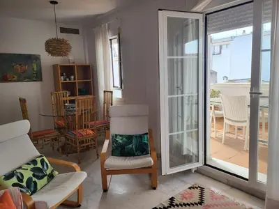 a living room with a chair and a sliding glass door at Apartamento en el centro con garaje, terraza, wifi, climatización y piscina in Sanlúcar de Barrameda