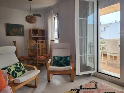 a living room with a chair and a window at Apartamento en el centro con garaje, terraza, wifi, climatización y piscina in Sanlúcar de Barrameda