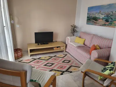 a living room with a couch and a tv at Apartamento en el centro con garaje, terraza, wifi, climatización y piscina in Sanlúcar de Barrameda