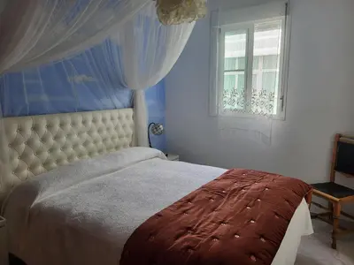 a bedroom with a large bed and a window at Apartamento en el centro con garaje, terraza, wifi, climatización y piscina in Sanlúcar de Barrameda
