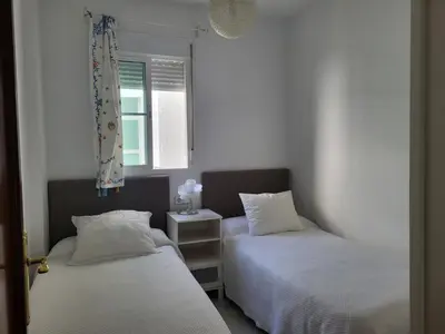 two beds in a small room with a window at Apartamento en el centro con garaje, terraza, wifi, climatización y piscina in Sanlúcar de Barrameda